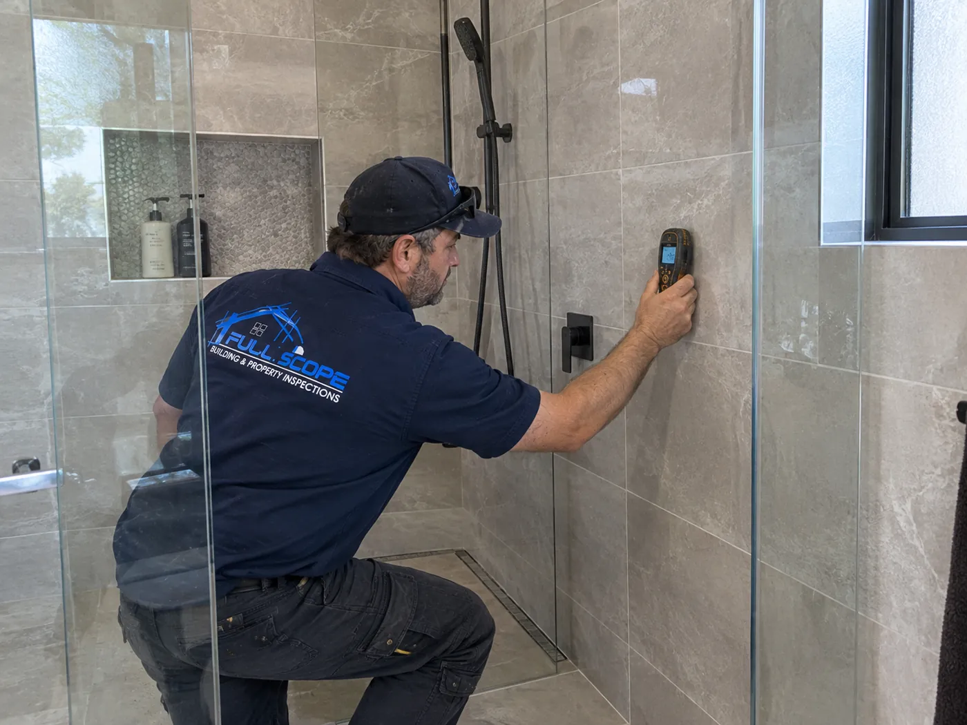 Moisture meter being used on a tiled shower wall